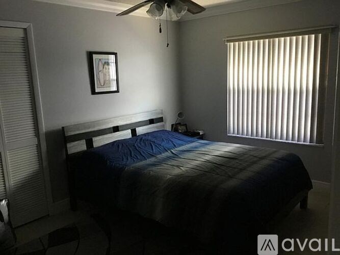 A bedroom with a bed, a ceiling fan, and a window with blinds.