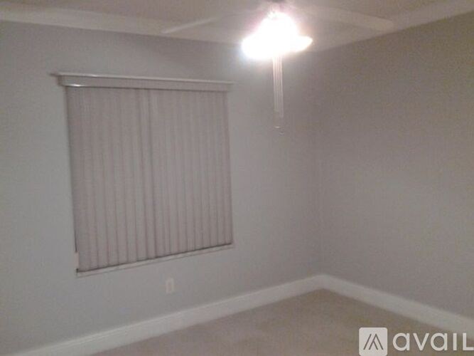 A room with a window covered by a blind and a light on.