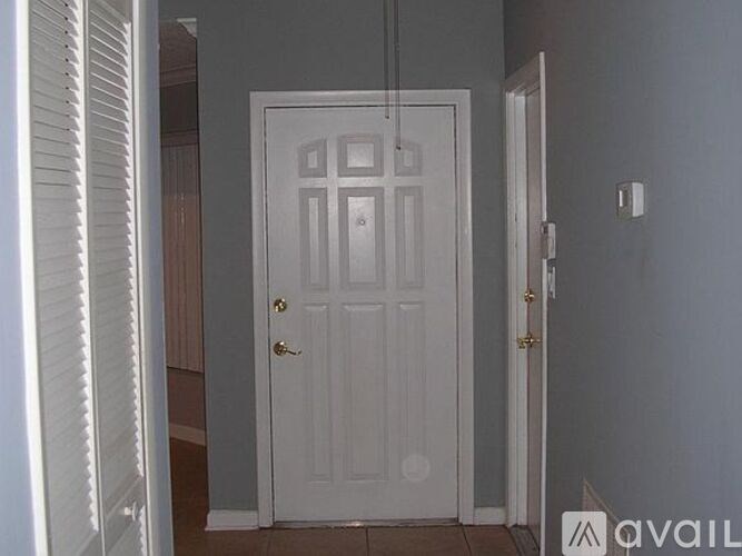 A white door is in a room with a grey wall.