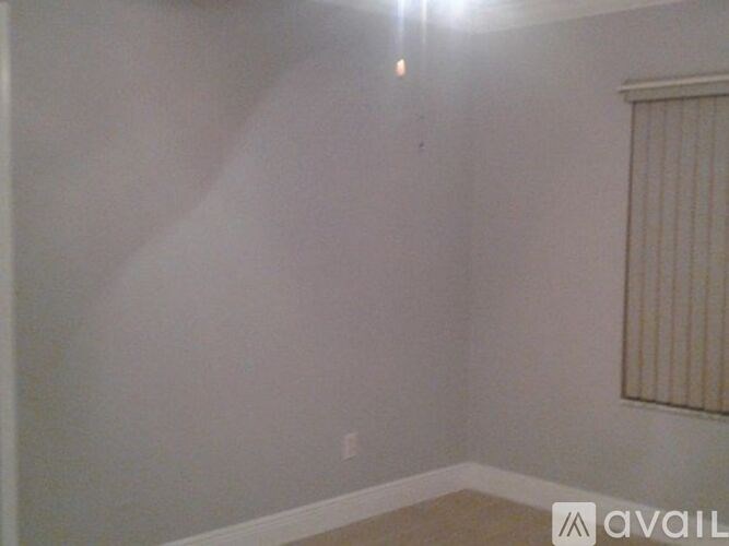 A room with a window covered by blinds and a light on the wall.