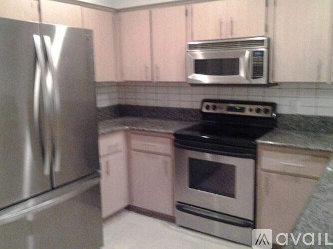 A kitchen with a stainless steel refrigerator and a black stove top oven.