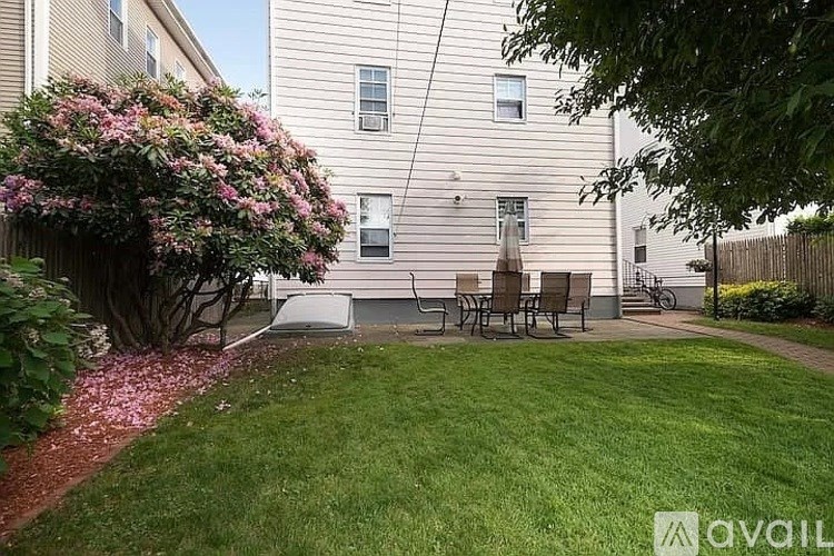 A small garden with a bench and a tree in front of a building.