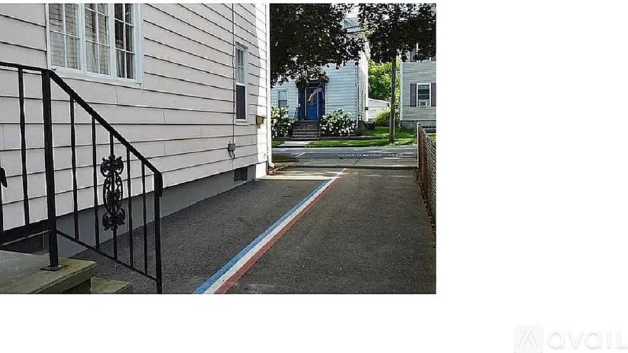 A white house with a black railing and a red, white and blue stripe on the sidewalk.