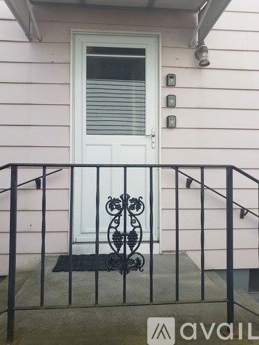 A white door with a black wrought iron gate and mat in front of a pink house.