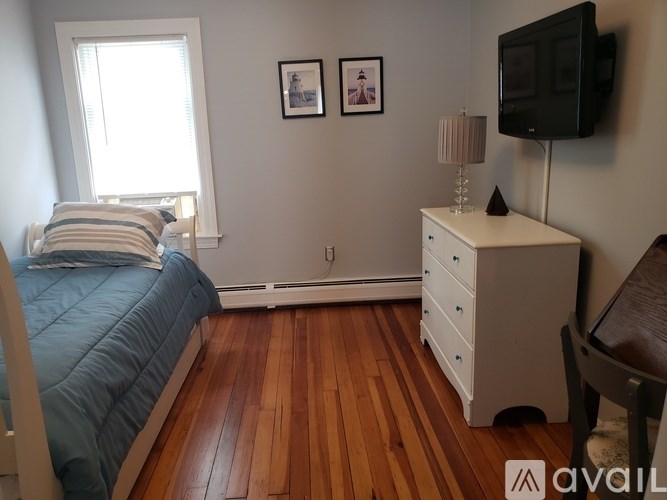 A bedroom with a bed, dresser, and a window.