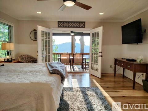 A bedroom with a large bed and a television on the wall.