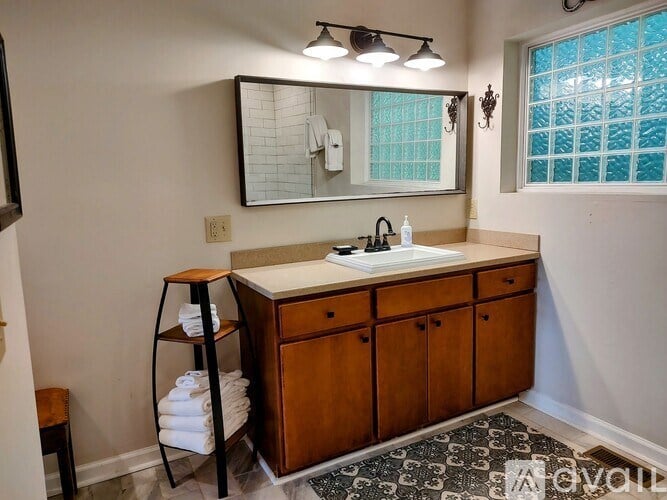 A bathroom with a wooden vanity and a mirror above the sink.