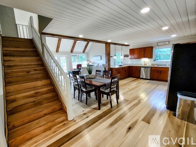 A wooden staircase leads to a brightly lit open plan kitchen and dining area.
