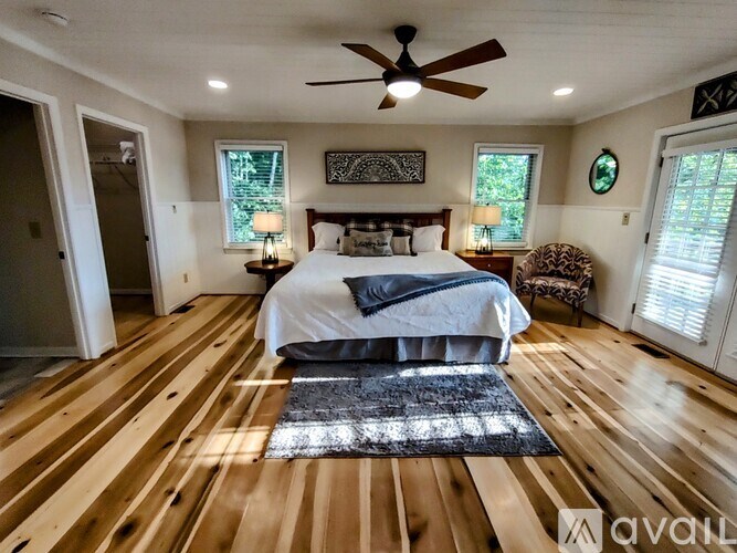 A bedroom with a bed, a chair, and a ceiling fan.