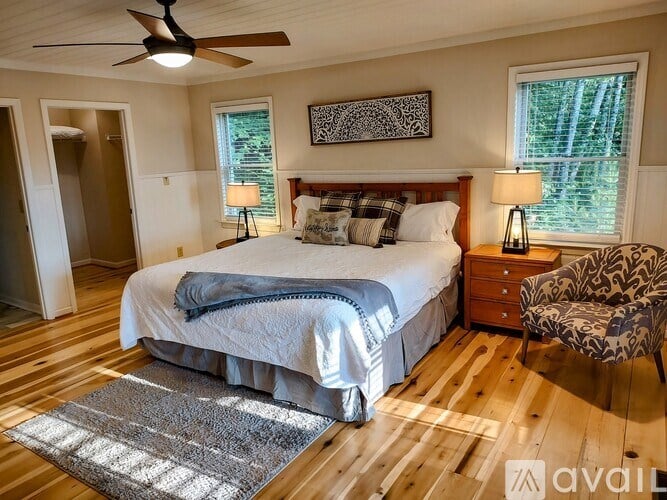 A bedroom with a large bed, a ceiling fan, and a chair.