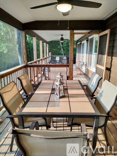 A table with chairs is on a screened porch.