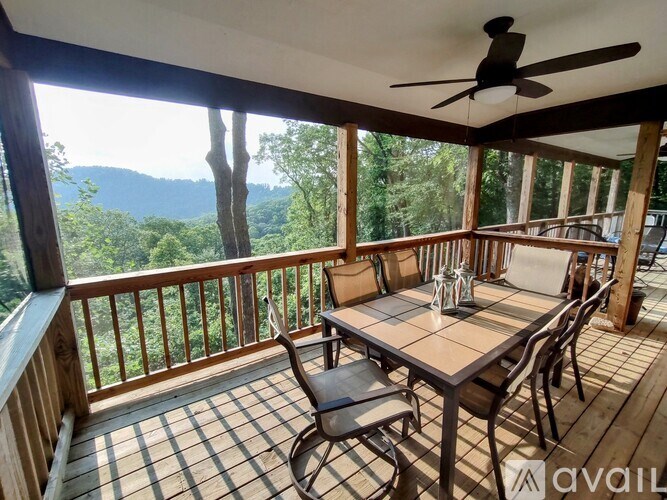 A wooden deck with a table and chairs overlooking a forest.