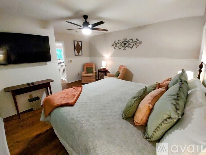A bedroom with a bed, a ceiling fan, and a television mounted on the wall.