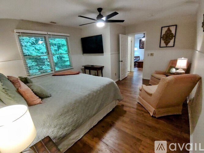 A bedroom with a bed, chair, and a ceiling fan.
