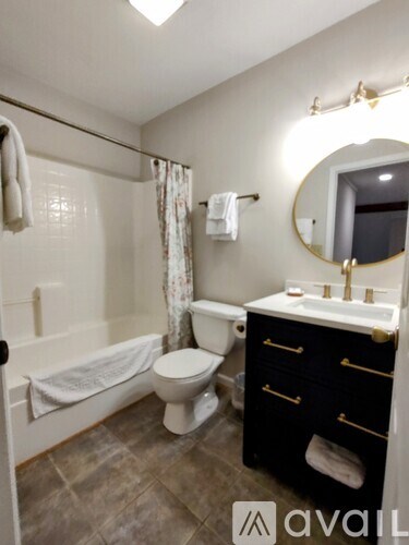 A bathroom with a toilet, sink, and a round mirror.
