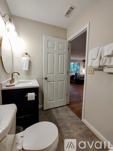 A bathroom with a toilet, sink, mirror, and towel rack.