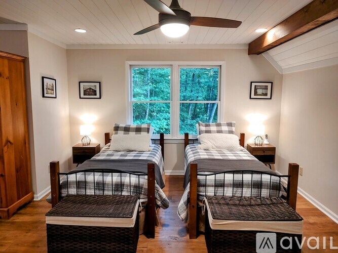 Two twin beds in a room with a window and a ceiling fan.