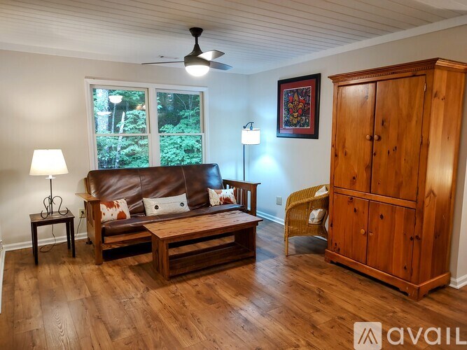 A living room with a brown couch, a wooden coffee table, and a wooden cabinet.