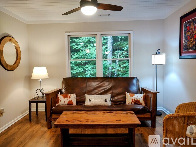 A living room with a brown leather couch and a wooden table.