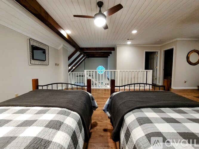 Two beds in a room with wooden floors and a ceiling fan.