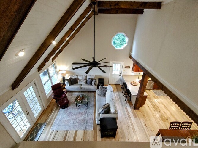 A living room with a couch, chairs, and a table with a fan hanging from the ceiling.