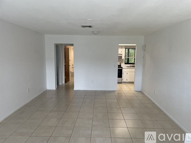 A spacious room with tiled flooring and a doorway leading to another room.