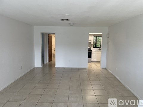 A spacious room with tiled flooring and a doorway leading to another room.