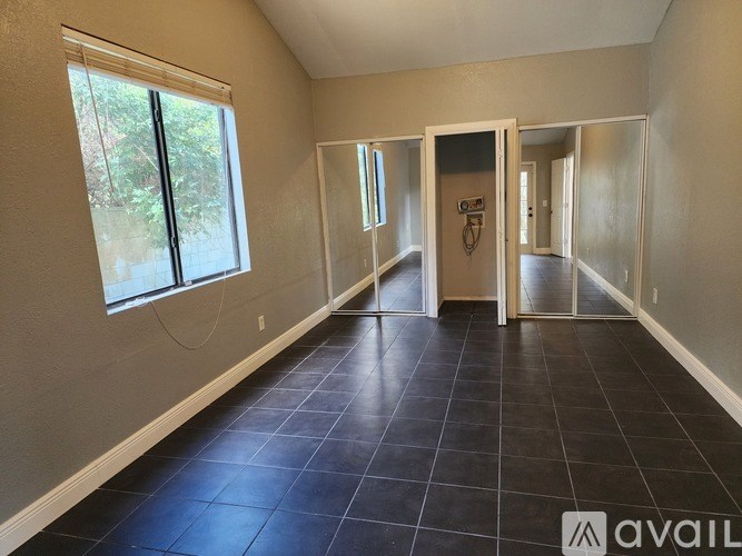 A spacious room with black tiled flooring and white walls.