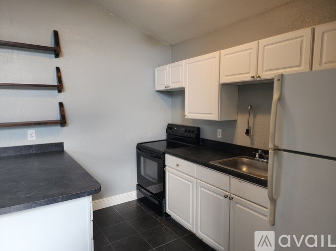 A kitchen with white cabinets and black countertops.