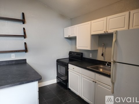 A kitchen with white cabinets and black countertops.