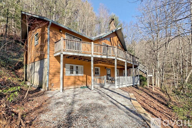 A wooden house with a balcony and a porch surrounded by trees.