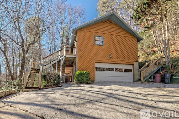 A wooden house with a garage and stairs leading to the upper floor.