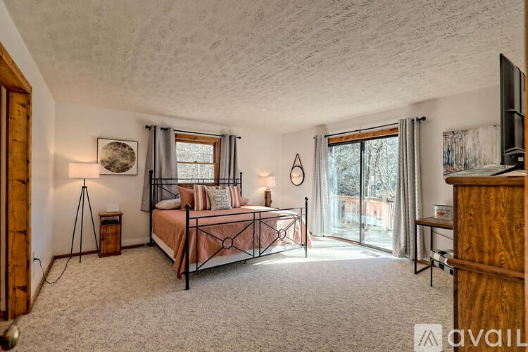 A bedroom with a bed, dresser, and window.