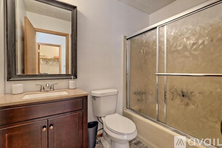 A bathroom with a toilet, sink, and mirror.