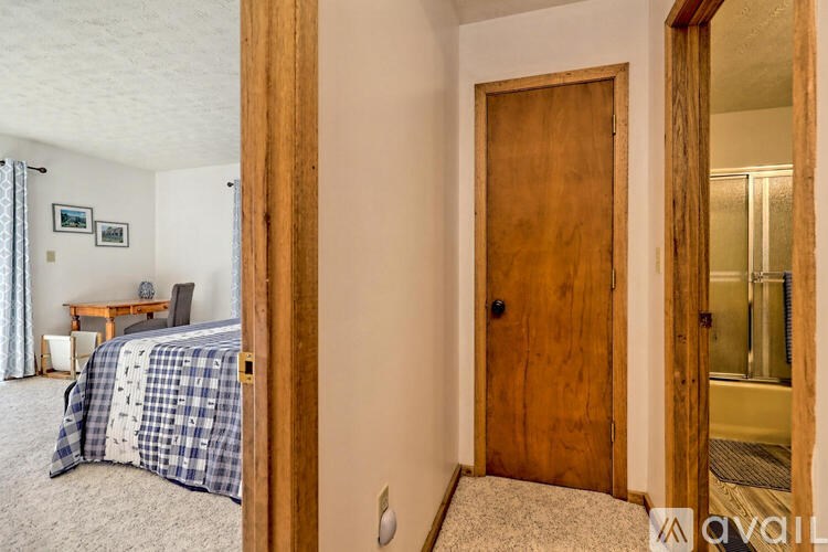 A bedroom with a bed, a table, and a wooden door.