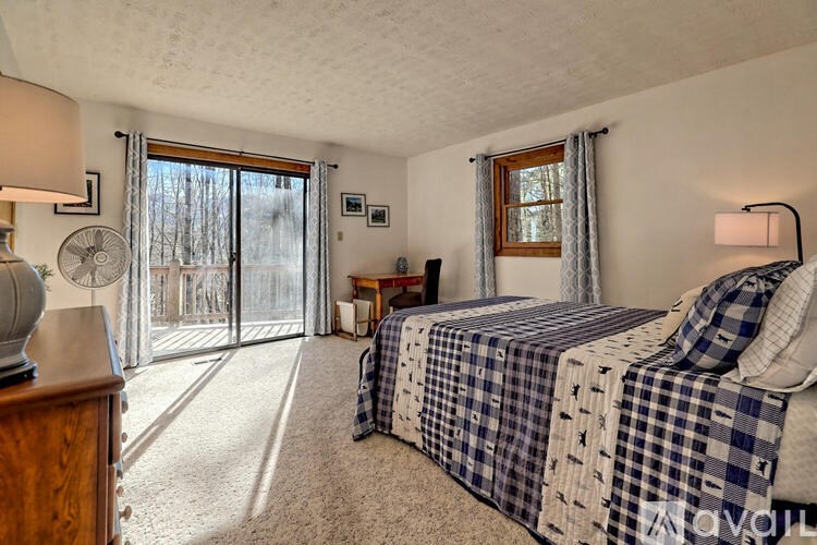 A bedroom with a bed, a fan, and a window with curtains.