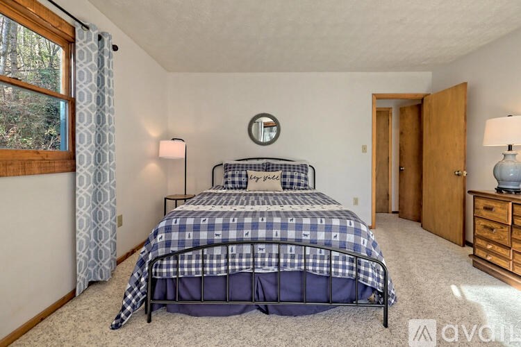 A bedroom with a bed, nightstand, and window.