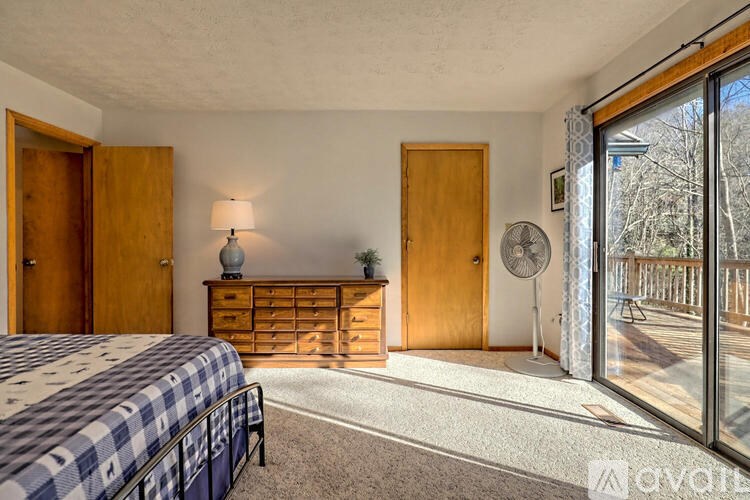A bedroom with a bed, dresser, and sliding glass doors.