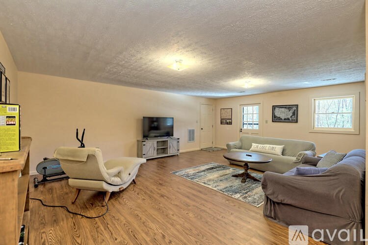 A living room with a grey couch, a white chair, and a wooden floor.
