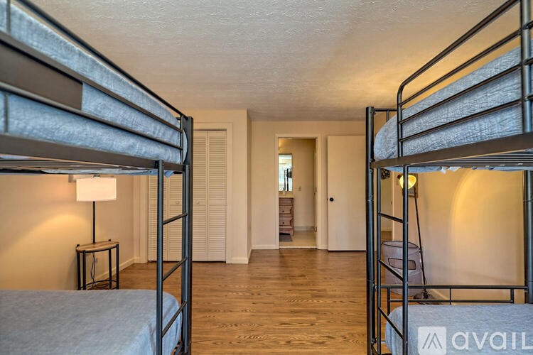 A room with two bunk beds and a small table with a lamp on it.