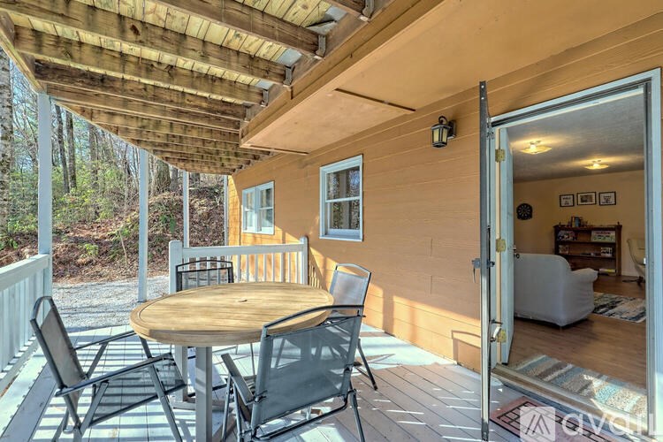 A wooden table and chairs are on a porch.