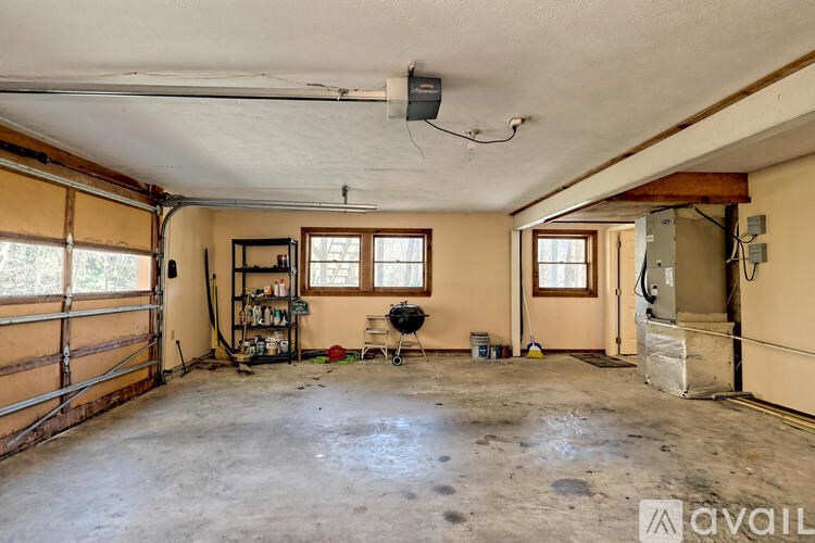 A large empty room with a garage door on the left and a window on the right.