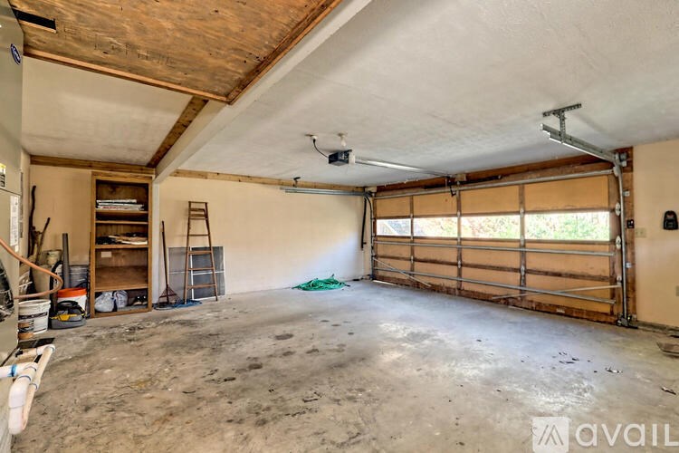 A large, empty room with a ladder and a fan.
