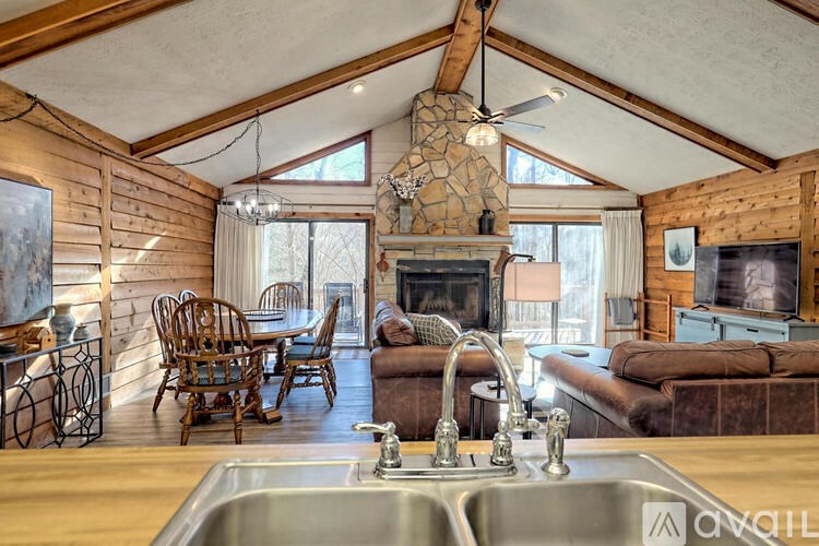 A cozy kitchen with a stone fireplace and wooden chairs.