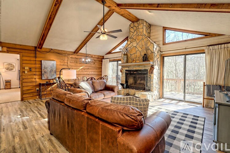 A living room with a brown leather couch and a fireplace.