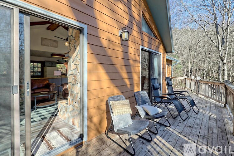 A wooden deck with chairs and a house in the background.
