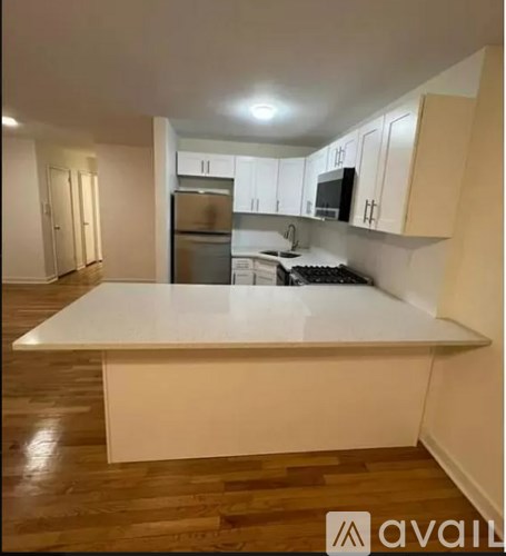 A kitchen with a white countertop and wooden floors.