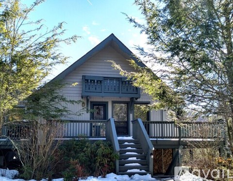 A house with a grey roof and a balcony surrounded by trees.