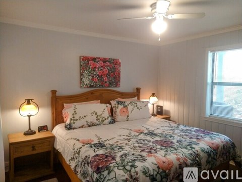 A bedroom with a floral bedspread and a wooden headboard.