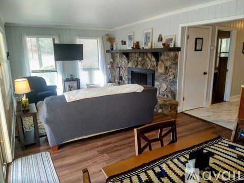A bedroom with a stone fireplace and a grey bed.